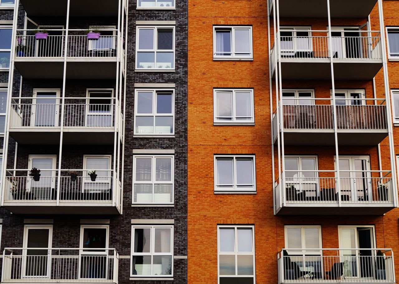 Home Detailed view of a modern apartment building's exterior with balconies and glass windows.