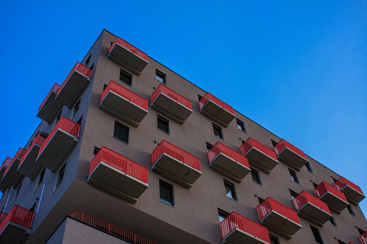 Home Low-angle view of a Vienna residential building with red balconies against a clear blue sky.
